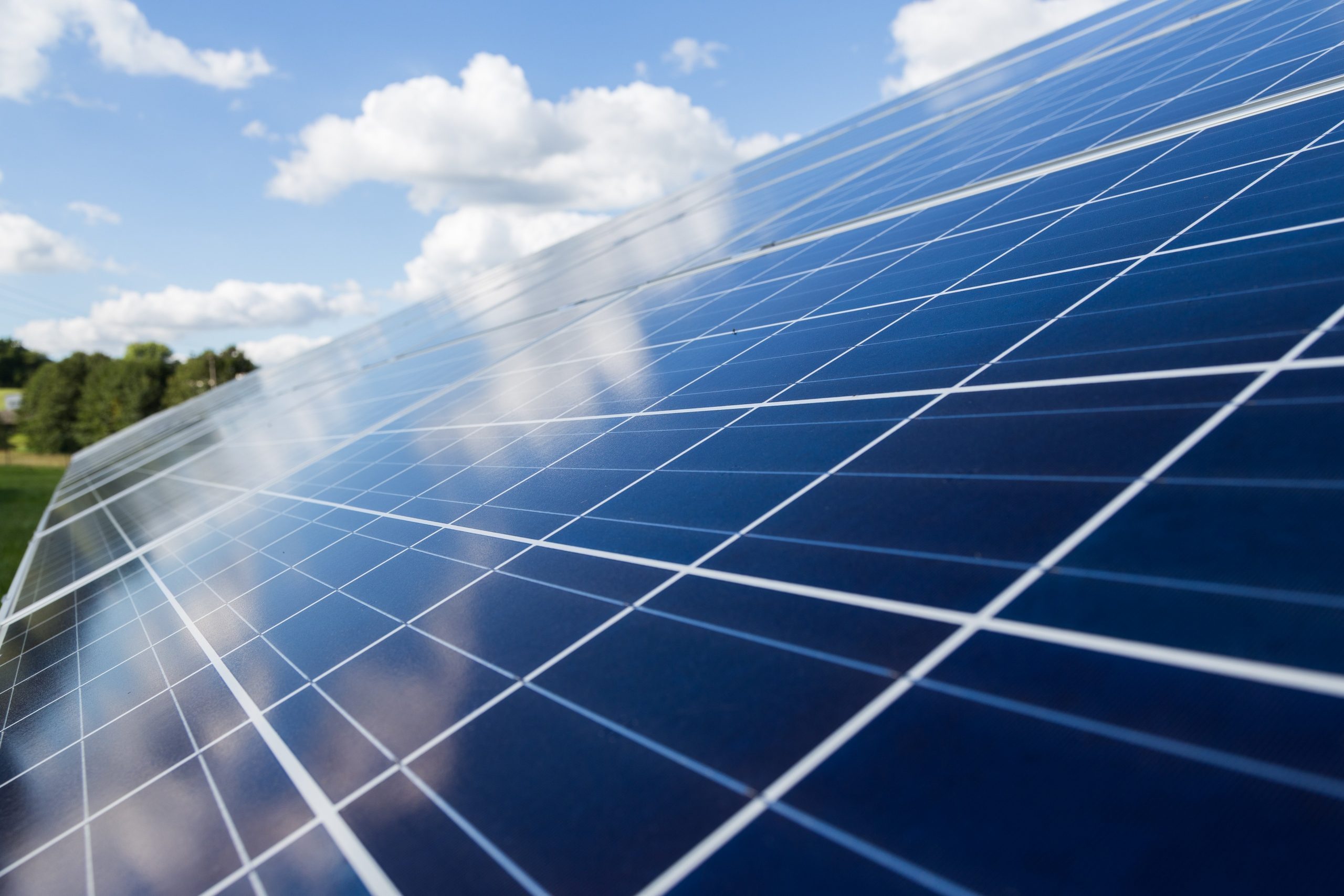 Rangées de panneaux solaires photovoltaïques s'étendant sous un ciel nuageux.